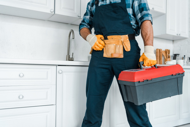 cropped view of handyman in uniform standing and holding toolbox  - Φωτογραφία, εικόνα
