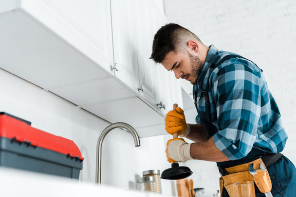 селективный фокус ремонтника, держащего плунжер на кухне
  - Фото, изображение