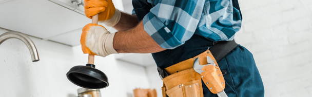 Panoramaaufnahme von Handwerker mit Werkzeuggürtel, der Kolben in Küche hält  - Foto, Bild
