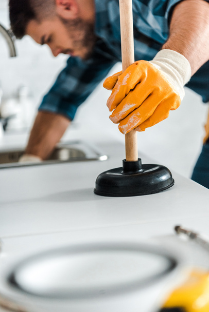 selective focus of man holding plunger in kitchen  - Photo, Image