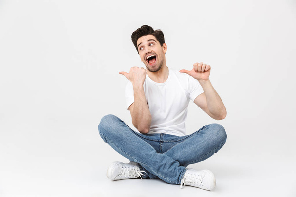 Excited young man posing isolated over white wall background pointing. - Фото, зображення