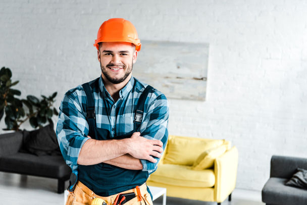 happy handyman looking at camera while standing with crossed arms  - Photo, Image