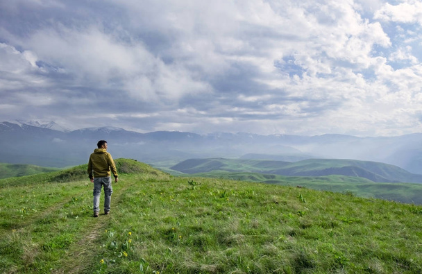 Beautiful landscape, man standing on the hill in front of mountains - Fotoğraf, Görsel