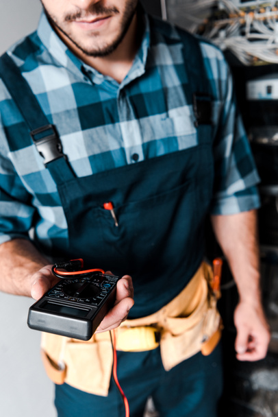 cropped view of bearded technician holding digital meter  - Photo, Image