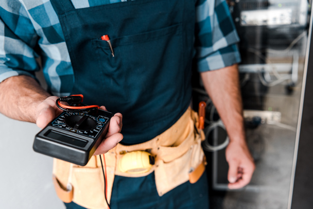 cropped view of technician holding digital meter near wires and cables  - 写真・画像