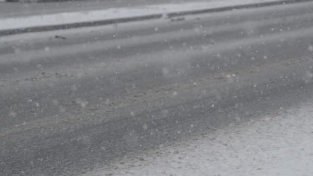 Slow Motion, Close Up, Dof: Onberispelijke witte sneeuwvlokken vallen neer op de vuile asfaltweg. Cool uitzicht op de auto paden gemaakt in bruine sneeuw. De slechte weersomstandigheden houden het verkeer van de snelweg. - Video