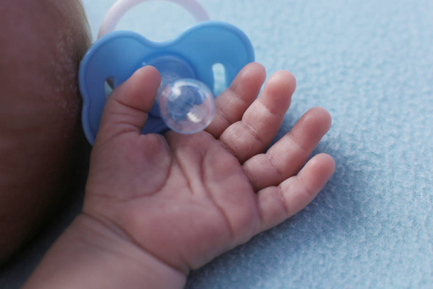 Partes del cuerpo de un pequeño bebé recién nacido de un mes de edad, un fondo azul y un estado de ánimo tierno
 - Foto, imagen