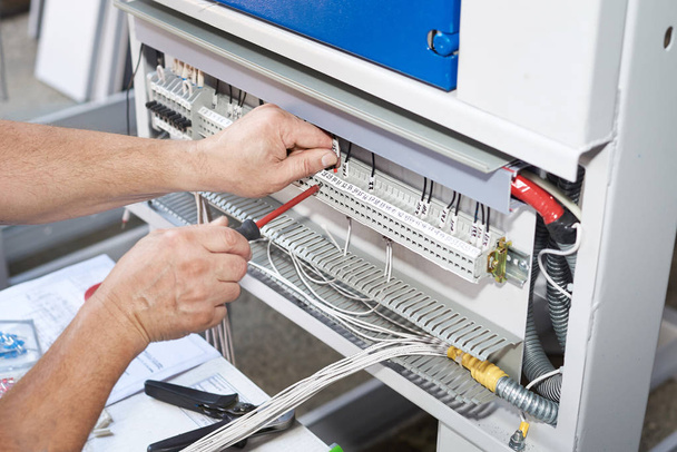 The electrician performs the installation and configuration of high-voltage equipment. - Photo, Image