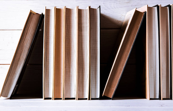 Παλιά βιβλία με κίτρινες σελίδες στέκονται σε ένα λευκό ξύλινο ράφι - Φωτογραφία, εικόνα