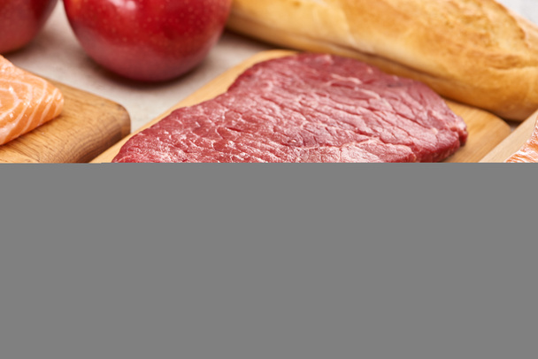 Fresh raw meat on wooden cutting board near lemon6 apples and baguette - Photo, Image