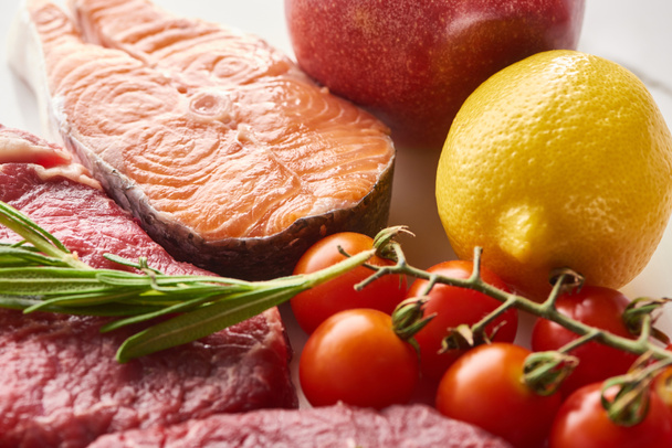 Vue rapprochée du steak de saumon cru près de la viande avec brindilles de romarin, citron et branche de tomates
 - Photo, image