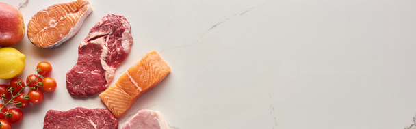 Панорамний знімок сирого м'яса, риби та птиці біля помідорів, лимона та яблука на мармуровій поверхні з місцем для тексту
 - Фото, зображення