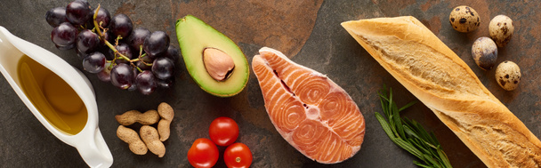 Панорамный снимок сырого лосося рядом с овощами, виноградом, перепелиными яйцами, арахисом, багетом и оливковым маслом на мраморной поверхности
 - Фото, изображение