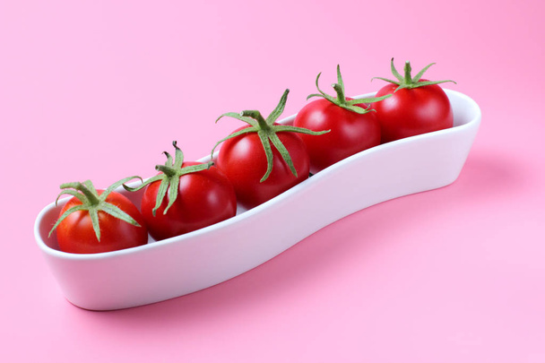 Cherry tomatoes in a small ceramic stand on a pink background, bright natural colors, high contrast. - Foto, Imagen