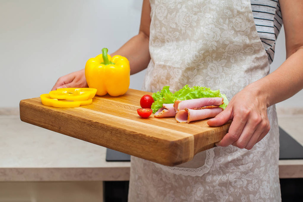 Жінка тримає піднос з перцем, помідорами, ковбасою, салатом і розкиданими спеціями, крупним планом
 - Фото, зображення