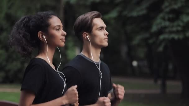 Handsome Young Couple in Headphones Looking Relaxed Running in Park Side view Close Up Girl on the Left. - Footage, Video