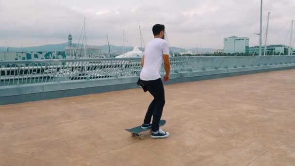 Skateboarder monta un monopatín en la moderna terraza de la ciudad
. - Metraje, vídeo