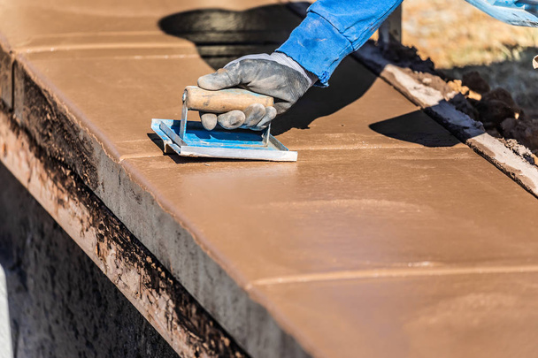 Trabalhador de construção usando mão Groover em cimento molhado formando coping em torno de nova piscina - Foto, Imagem