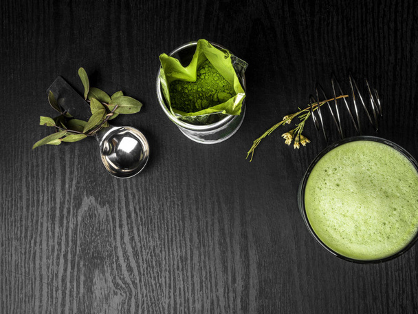 Hot green tea latte with green leaves and metal spoon, whisk, antioxidants rich drink, free space for text - Photo, Image