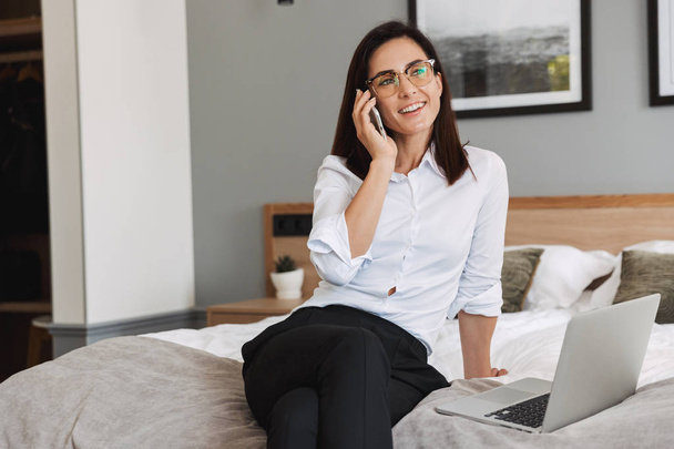 Portrait of pleased adult businesswoman talking on smartphone an - Photo, image