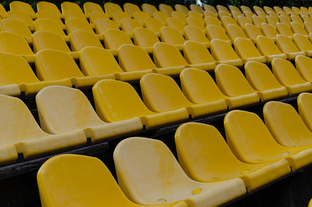 Ряди порожніх пластикових жовтих стільців на стадіоні. На відкритому повітрі
 - Фото, зображення