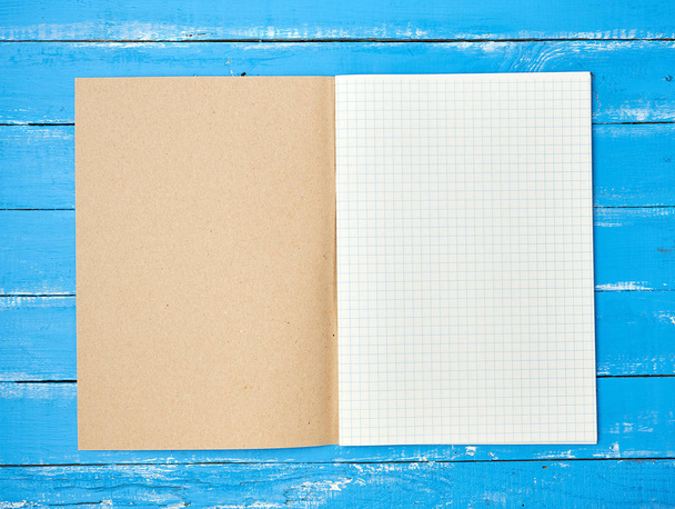 otevřít překontrolený školní notebook na modrém dřevěném pozadí - Fotografie, Obrázek