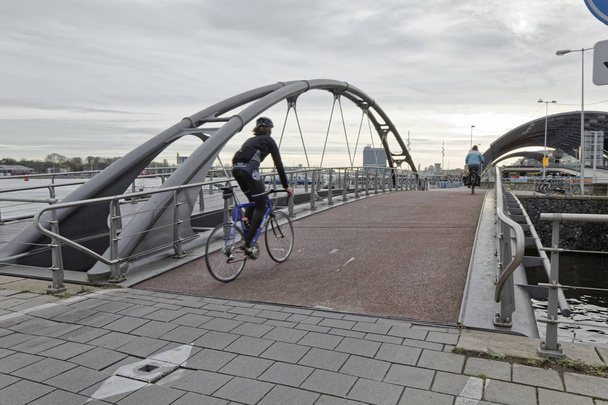オランダ, アムステルダム;2011年10月9日、水路に架かる橋の上のバイカー - 社説 - 写真・画像