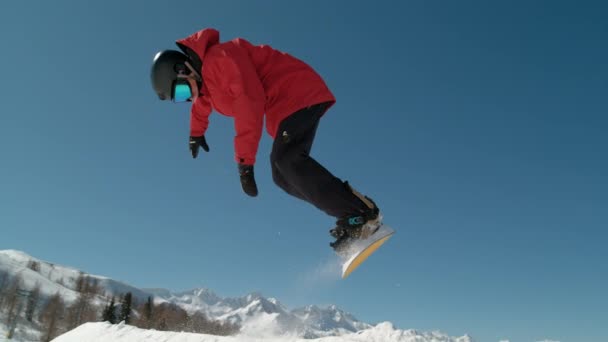 Zeitlupe aus nächster Nähe: Extrem-Snowboarder springen im großen Gebirgsskigebiet. Detail des Snowboard-Starts im präparierten Snowpark. Snowboardspringen am sonnigen Wintertag im snb park - Filmmaterial, Video