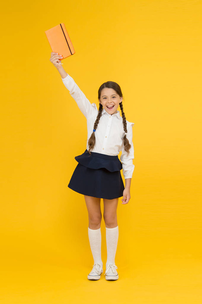 Excited about knowledge. happy girl study hard with notebook. reading and writing. small girl child with book. literature lesson. childrens literature. back to school. Pupil at book store or library - Φωτογραφία, εικόνα