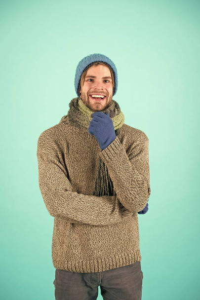Winter fashion knitted clothes. Knitted accessories as hat and scarf. Man in knitted hat and scarf winter fashion season. Man wear knitted clothes turquoise background. Winter accessories concept - Foto, Imagen