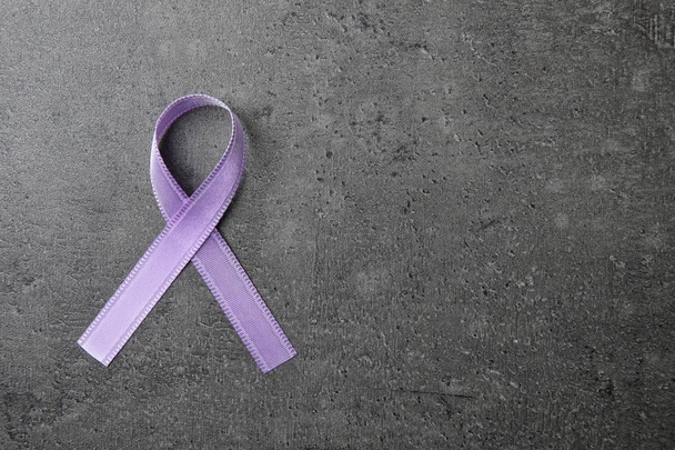 Purple ribbon on grey stone background, top view with space for text. Domestic violence awareness - Foto, Bild