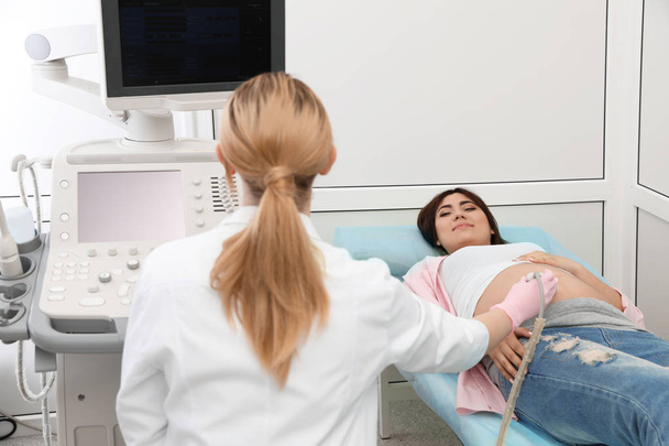 Junge Schwangere unterzieht sich in moderner Klinik einer Ultraschalluntersuchung - Foto, Bild