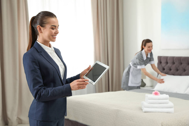 Housekeeping manager with tablet checking maid work in hotel room. Space for text - Foto, Imagem