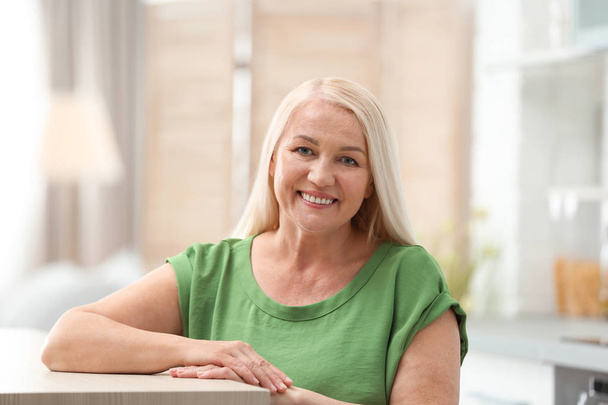 Portrait of happy mature woman at table indoors - Photo, image