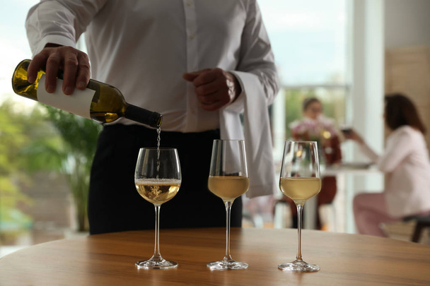 Waiter pouring wine into glass in restaurant, closeup - Foto, afbeelding