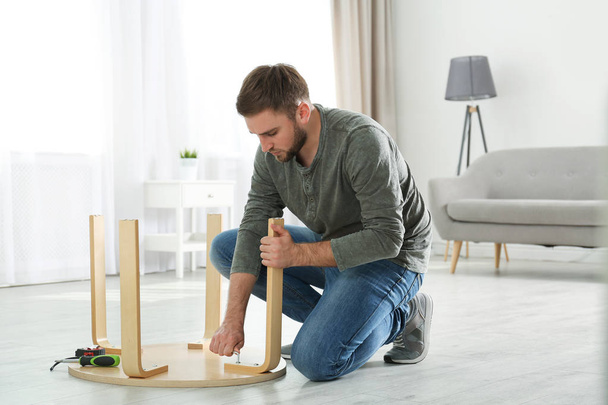 Young working man repairing table at home - Foto, Bild
