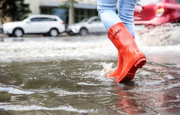 Woman with rubber boots running in puddle, closeup. Rainy weather - Foto, Bild