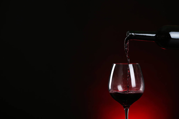 暗い背景にボトルからグラスにワインを注ぐ, テキストのためのスペース - 写真・画像