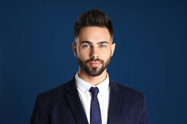 Portrait of handsome young man in office suit on color background - Foto, Bild