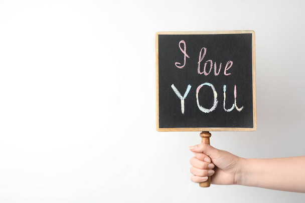 Young woman holding chalkboard with words I LOVE YOU on white background. Space for text - Foto, imagen