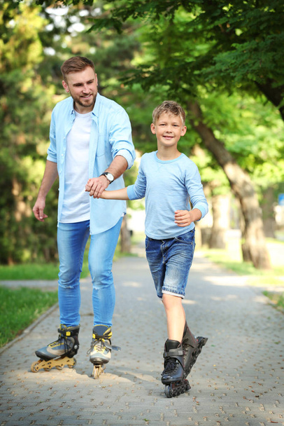 Father and son roller skating in summer park - Fotografie, Obrázek