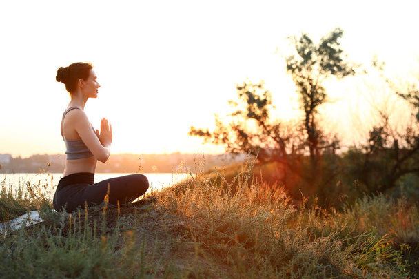 Young woman practicing yoga outdoors on sunset. Zen meditation - Fotó, kép