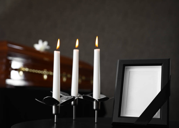 Black photo frame with burning candles on table in funeral home - Zdjęcie, obraz