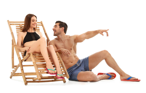 Young couple with sun lounger on white background. Beach accessories - Foto, Imagen