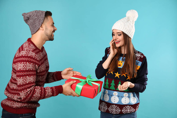 Ζευγάρι φορώντας Χριστουγεννιάτικα πουλόβερ σε μπλε φόντο - Φωτογραφία, εικόνα
