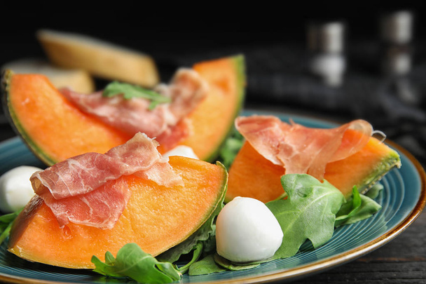 Fresh melon with prosciutto, mozzarella and arugula on plate, closeup - Photo, image