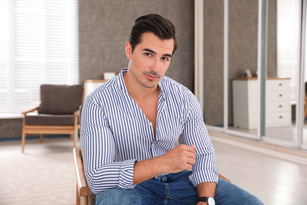 Portrait on handsome young man sitting in chair indoors - Photo, image