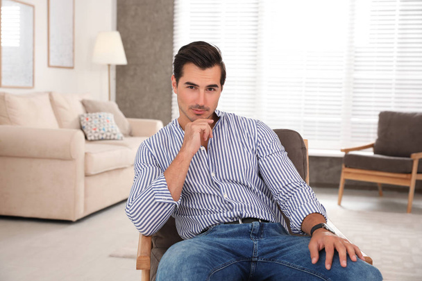 Portrait on handsome young man sitting in chair indoors - Foto, Imagem