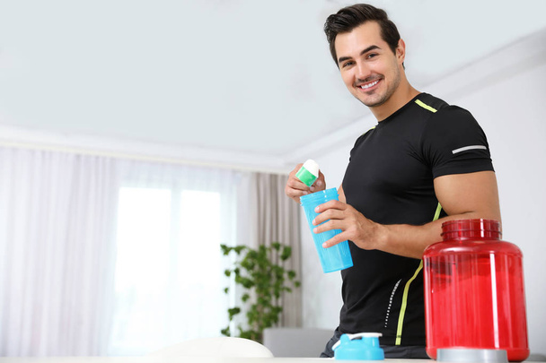 Young athletic man preparing protein shake at home, space for text - Photo, Image
