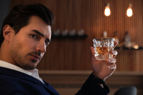 Young man with glass of whiskey in bar - Fotoğraf, Görsel